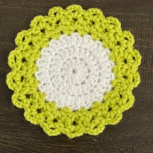 Peut inclure: Un dessous de verre crochet&eacute; avec un centre blanc et une bordure vert lime. Le dessous de verre a un bord festonn&eacute;.