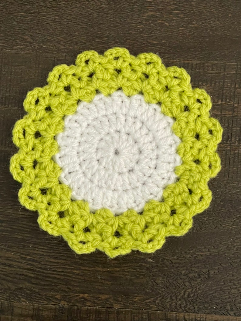 Peut inclure: Un dessous de verre crochet&eacute; avec un centre blanc et une bordure vert lime. Le dessous de verre a un bord festonn&eacute;.