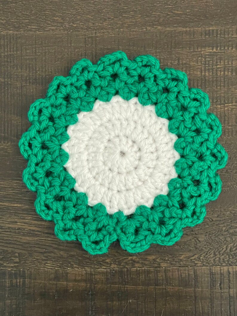 Peut inclure: Un dessous de verre crochet&eacute; vert et blanc avec un bord festonn&eacute;.