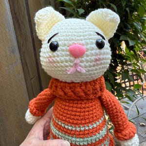 Pu&ograve; includere: Bambola a forma di gatto all'uncinetto fatta a mano con testa bianca e orecchie color crema. Il gatto indossa un maglione arancione con strisce verdi. La bambola ha occhi neri, naso rosa e bocca rosa.