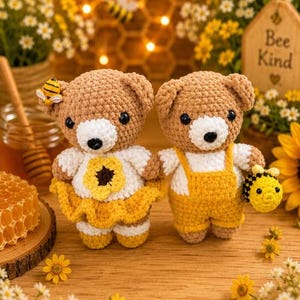 K&ouml;nnte beinhalten: Zwei geh&auml;kelte Teddyb&auml;ren mit hellbraunen Garnk&ouml;rpern und wei&szlig;en Schnauzen. Ein B&auml;r tr&auml;gt ein wei&szlig;es Oberteil mit einer gelben Blume und einem gelben Rock sowie einer kleinen Biene am Ohr. Der andere B&auml;r tr&auml;gt ein wei&szlig;es Oberteil mit gelber Latzhose und h&auml;lt eine kleine geh&auml;kelte Biene.