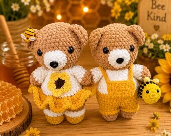 Peut inclure: Deux ours en peluche crochetés avec des corps en fil marron clair et des museaux blancs. Un ours porte un haut blanc avec une fleur jaune et une jupe jaune, avec une petite abeille sur l'oreille. L'autre porte un haut blanc avec une salopette jaune et tient une petite abeille crochetée.