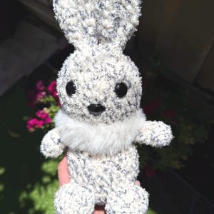 Peut inclure: Un lapin en peluche fait &agrave; la main, avec un corps blanc duveteux parsem&eacute; de bleu fonc&eacute;. Il a de grands yeux noirs, un col en fausse fourrure blanche et de longues oreilles dress&eacute;es. C'est un jouet doux.