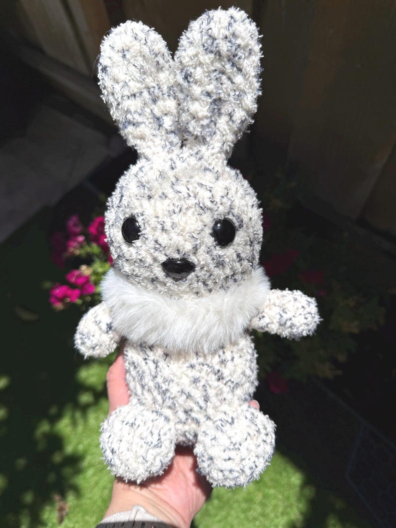 Peut inclure: Un lapin en peluche fait &agrave; la main, avec un corps blanc duveteux parsem&eacute; de bleu fonc&eacute;. Il a de grands yeux noirs, un col en fausse fourrure blanche et de longues oreilles dress&eacute;es. C'est un jouet doux.