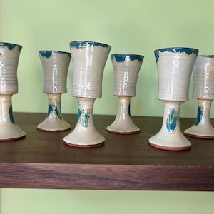 Puede incluir: Juego de seis copas de cerámica con bordes azul turquesa y bases blancas. Las copas tienen un aspecto único y artesanal.