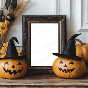 May include: Two orange jack-o'-lantern pumpkins with black witch hats sit on a wooden surface in front of a black framed picture with a white background.