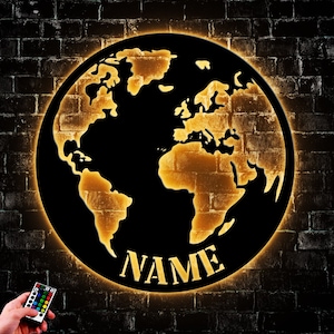May include: A black and gold world map wall light with a customizable name plate. The light is illuminated with a warm glow and has a remote control.