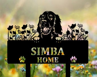 May include: Black metal garden stake featuring a dog silhouette above a sign that reads "SIMBA HOME." The sign has paw prints and is set against a colorful floral background. The dog is smiling with its tongue out.