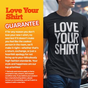 May include: A black t-shirt with white text that reads "Love Your Shirt". The text is in a bold, sans-serif font. The shirt is being worn by a person standing in front of a crowd. The image includes text that reads "Love Your Shirt Guarantee" and explains that if you don't love the shirt, you can return it, exchange it, or get a refund.