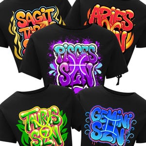 Peut inclure: Des crop tops noirs avec des motifs de signes du zodiaque de style graffiti. Les chemises pr&eacute;sentent les mots "SAGITTARIUS SZN", "ARIES SZN", "PISCES SZN", "TAURUS SZN" et "GEMINI SZN" dans des couleurs vives, pour les passionn&eacute;s d'astrologie.