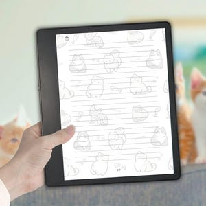 Może przedstawiać: Czarny tablet cyfrowy z białym ekranem, na którym widoczne są poziome linie oraz powtarzający się wzór jasnoszarych rysunków kotów i małych rybek. Liczba 57 znajduje się na dole pośrodku, a ikona domu w lewym górnym rogu ekranu.