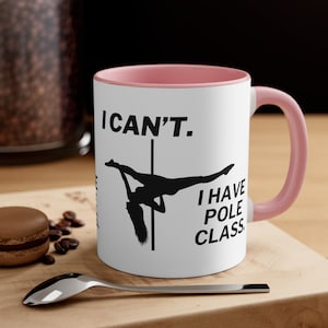 Può includere: Una tazza in ceramica bianca con un bordo e un manico rosa. La tazza ha una silhouette nera di una donna su un palo con il testo "I CAN'T. I HAVE POLE CLASS."