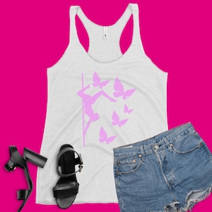 Könnte beinhalten: Ein weißes Tanktop mit einer pinkfarbenen Silhouette einer Person, die Pole Dance betreibt, mit Schmetterlingen um sie herum. Das Tanktop befindet sich auf einem rosa Hintergrund.
