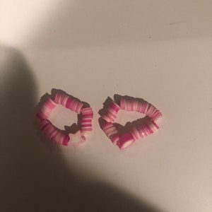 May include: Two pink and white bracelets made of stacked plastic beads. One bracelet has a white star charm.