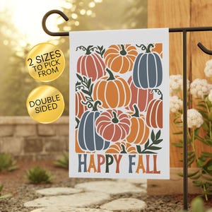 May include: A rectangular garden flag featuring a pattern of orange, red, and blue pumpkins with green stems and leaves. The text "HAPPY FALL" is printed in blue and orange letters at the bottom. Two gold circular badges state 2 SIZES TO PICK FROM and DOUBLE SIDED.