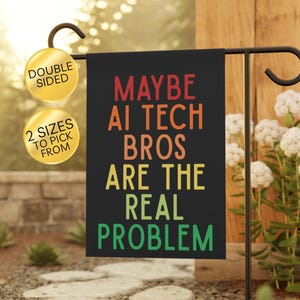 May include: A rectangular black garden flag hanging on a metal stand. The flag features multi-colored text that reads: MAYBE AI TECH BROS ARE THE REAL PROBLEM. Two gold circular badges are attached to the left, stating DOUBLE SIDED and 2 SIZES TO PICK FROM.