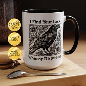 May include: A white ceramic mug with a black interior and handle, featuring a black and white illustration of a raven perched among flowers. The text "I Find Your Lack" is printed above the raven, and "Whimsy Disturbing" is printed below it.