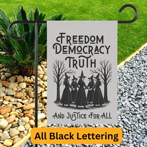 May include: A gray garden flag with black text and a black illustration of witches. The text reads "Freedom, Democracy, Truth, And Justice For All." The bottom of the flag has the text "All Black Lettering."