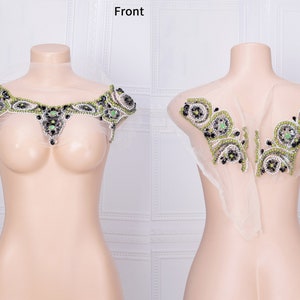 May include: A green and black beaded embellishment with a sheer fabric backing. The embellishment is shown on a white mannequin, with the front and back views displayed.