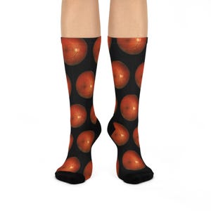 May include: A pair of black socks with a repeating pattern of red and orange eye images.