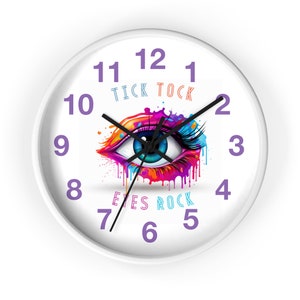 May include: White round wall clock with black hands and purple numbers. The clock face features a colourful eye with dripping paint and the text "Tick Tock" and "Eyes Rock".