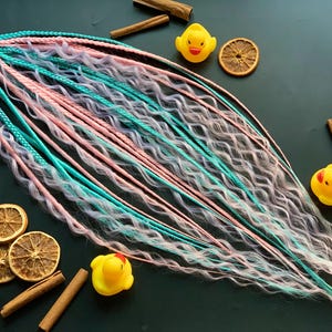 smooth bright double ended dreadlocks and tighter braids with thin curls in light pink turquoise and lavender colors for dread extensions