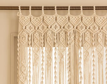 Puede incluir: Cortina de macramé color crema con intrincados patrones geométricos y largas y fluidas borlas. La cortina está suspendida de una barra marrón oscuro, añadiendo un toque bohemio a cualquier ventana o puerta. El diseño artesanal añade textura e interés visual.