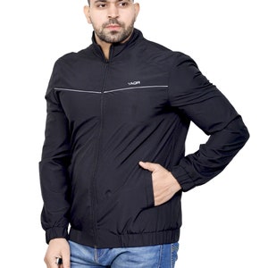 Peut inclure: Une veste noire zippée avec une bande blanche et le mot "YADR" sur le devant. La veste a un col montant et des manches longues.
