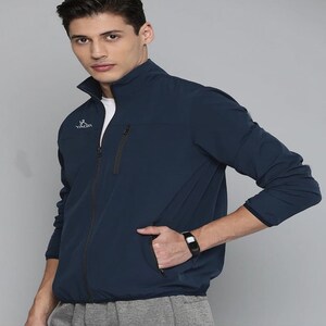 May include: A navy blue jacket with a zip closure and a white logo that says "YAGR" on the left chest. The jacket has two zipped pockets on the front.