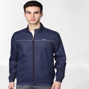 Könnte beinhalten: Eine marineblaue, leichte Jacke mit einem schwarzen Reißverschluss und einem weißen Streifen über der Brust. Die Jacke hat den Schriftzug "YAGR" in Weiß auf der rechten Brustseite.