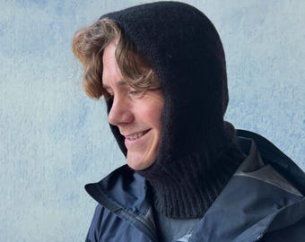 May include: A person wearing a black knit balaclava and a navy blue jacket with the logo "ARC'TERYX" on the left side of the chest.