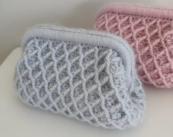 May include: Two small crochet pouches with a kiss-lock frame closure. One pouch is light blue and the other is light pink. Both feature a raised diamond lattice pattern across the exterior surface, created with thick yarn stitches.