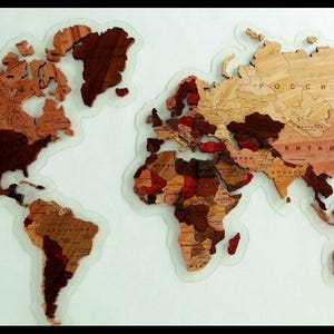 May include: A detailed wooden world map, featuring continents in shades of brown and tan, with a clear border. Country names are visible, making it a decorative and educational item for any room.