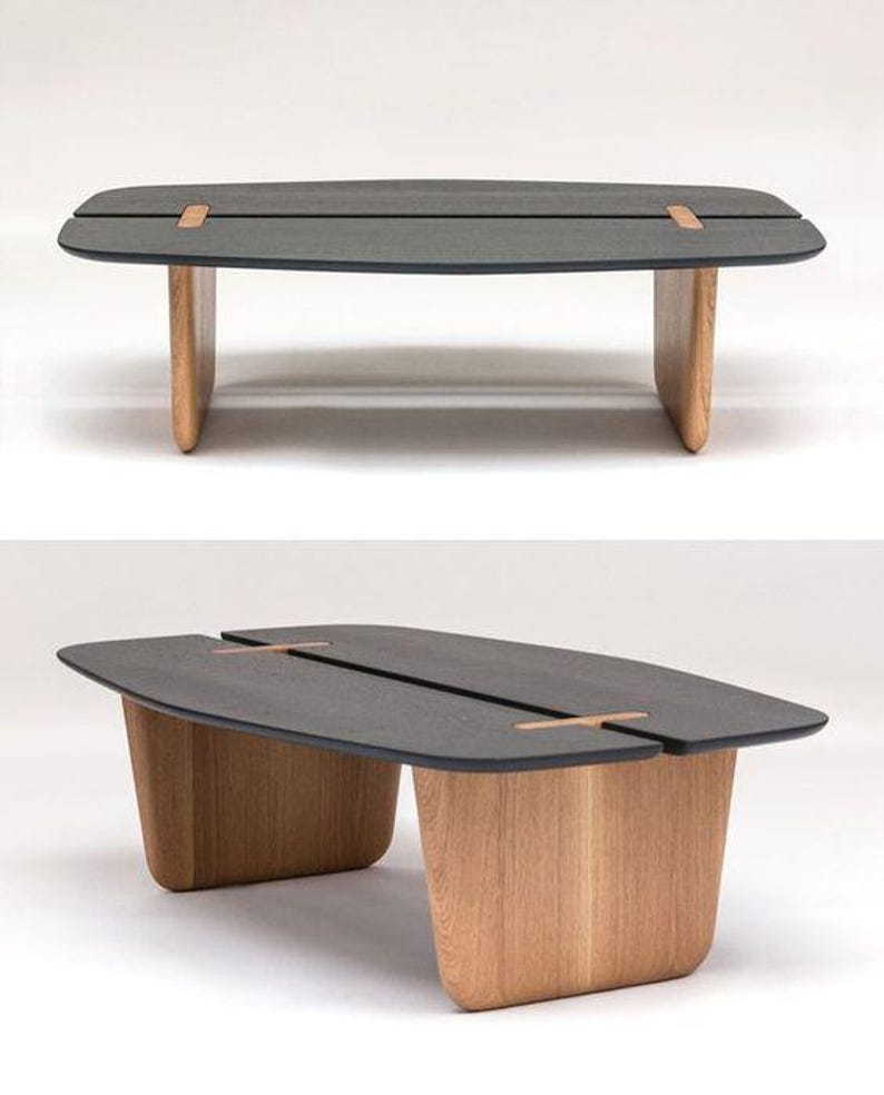 K&ouml;nnte beinhalten: Ein rechteckiger Couchtisch in Dunkelgrau mit einer einzigartigen geteilten Tischplatte und Holzbeinen. Der Tisch hat ein modernes Design und ist aus hochwertigen Materialien gefertigt.
