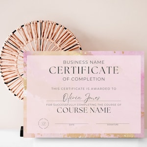 May include: A pink and gold watercolor certificate of completion with the text "BUSINESS NAME CERTIFICATE OF COMPLETION" and "THIS CERTIFICATE IS AWARDED TO Olivia Jones FOR SUCCESSFULLY COMPLETING THE COURSE OF COURSE NAME DATE SIGNATURE".