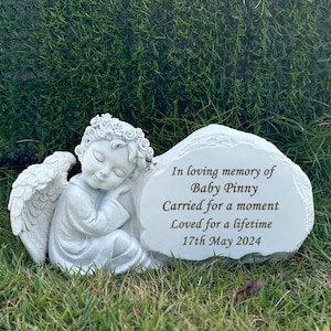 Könnte beinhalten: Weißer Steindenkmal mit einer schlafenden Engelsfigur. Der Stein trägt die Inschrift "In liebevoller Erinnerung an Baby Pinny Getragen für einen Moment Geliebt für ein Leben lang 17. Mai 2024".
