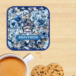 May include: A blue and white camouflage coaster with a floral design and a woman's face with sunglasses. The text #NAVYMOM is printed on the coaster.