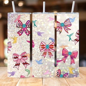 May include: Three stainless steel tumblers with a white glitter background and a pattern of pink bows and hummingbirds.