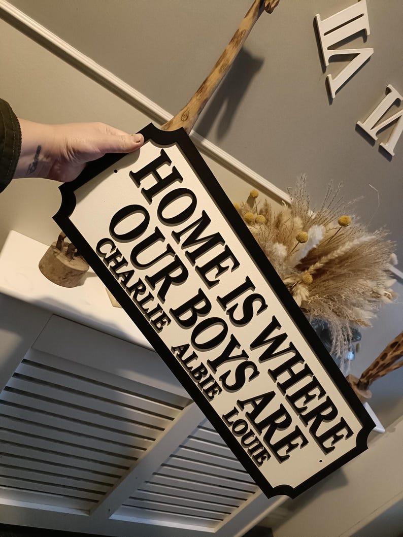 May include: Black and white sign with the text "Home is where our boys are" and the names Charlie, Albie, and Louie underneath.
