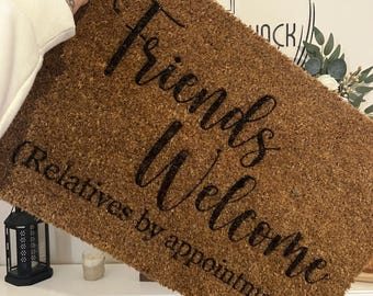 Può includere: Un tappetino per porta in fibra di cocco marrone con il testo "Friends Welcome (Relatives by appointment)" in lettere corsive nere.