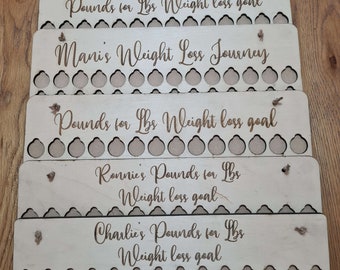 Może przedstawiać: Pięć drewnianych tablic z wygrawerowanym tekstem i kółkami do śledzenia utraty wagi. Tablice brzmią "Pounds for Lbs Weight loss goal", "Mani's Weight Loss Journey", "Ronnie's Pounds for Lbs Weight loss goal" i "Charlie's Pounds for Lbs Weight loss goal".
