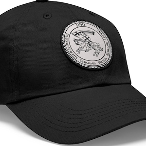 May include: Black baseball cap with a curved brim. The cap features a circular patch with the text "1190" and "Germania Prussia" surrounding a knight on horseback. The patch is in shades of gray and white.