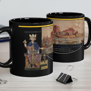 May include: Black ceramic mug with a white and gold design featuring a historical illustration of a king on a throne and a medieval city. The text "Kaiser Heinrich VI" and "Headquarters of the Teutonic Knights in Prussia" is printed on the mug.