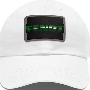 Op de afbeelding: Witte baseballpet met een zwart en groen patch waarop "FENDT" in een gestileerd lettertype staat.