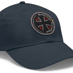 May include: A dark blue baseball cap with a circular patch featuring a black cross with red accents and the text "Bundeswehr Deutschland".