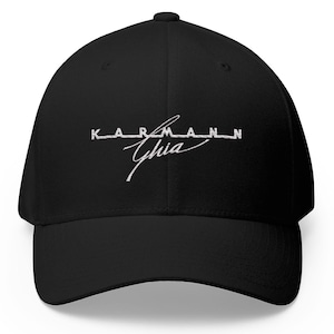 Pode incluir: Boné de beisebol preto com aba curva. O boné apresenta o texto bordado branco "KARMANN Ghia" em uma fonte estilizada na frente. O boné é feito de um tecido liso e tem um ajuste estruturado.