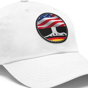 May include: White baseball cap with a round patch featuring a tree with the American flag as the canopy and the German flag as the roots.