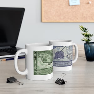 May include: Two white ceramic mugs with a green and blue design. The mug on the left features a green image of an airship with the text "Hundert Jahre" in German. The mug on the right features a blue image of a man in a uniform with the text "25" in blue.