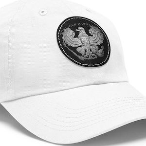 May include: White baseball cap with a black and white embroidered patch featuring a two-headed eagle with the text "CONGREGATIO PRI" around the edge.