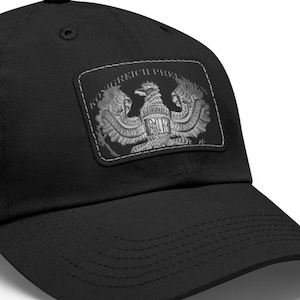 May include: Black baseball cap with a rectangular patch featuring a detailed silver eagle emblem. The patch includes the text "KONIGREICH PREU" and "FR". The cap has a curved brim and a top button.